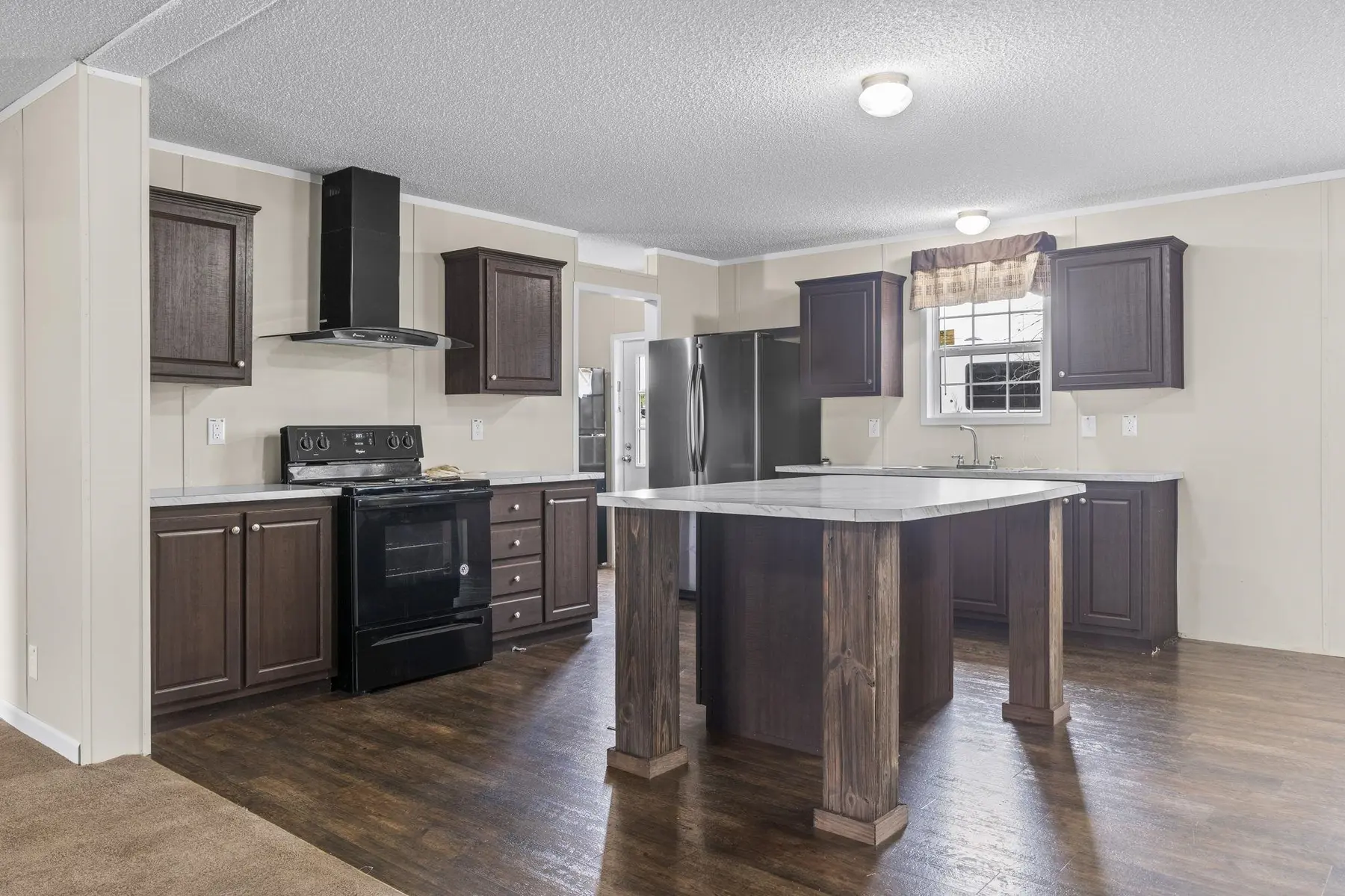 Kitchen with dark cabinetry, appliances and a large center island
