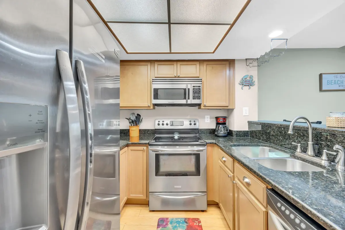 Kitchen with stainless-steel refrigerator, range, microwave, and wood cabinetry