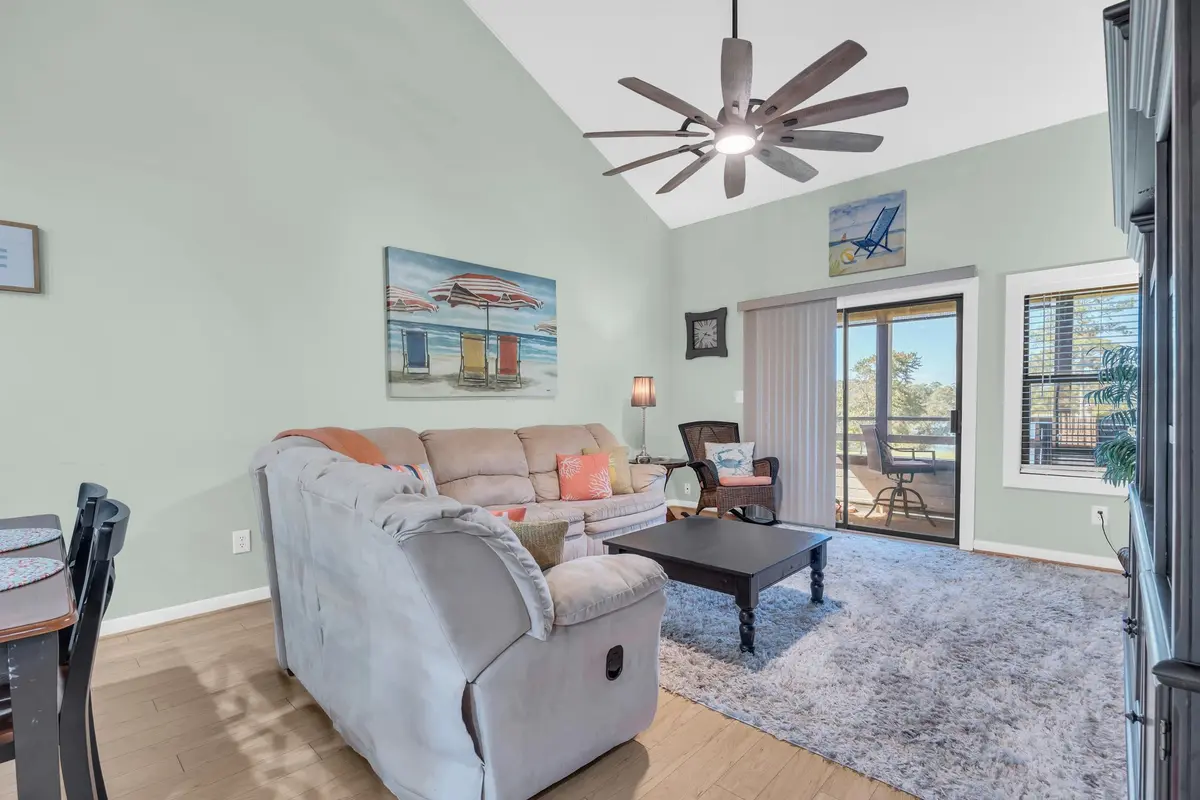 Living room with vaulted ceiling, seating, and screened-porch doors