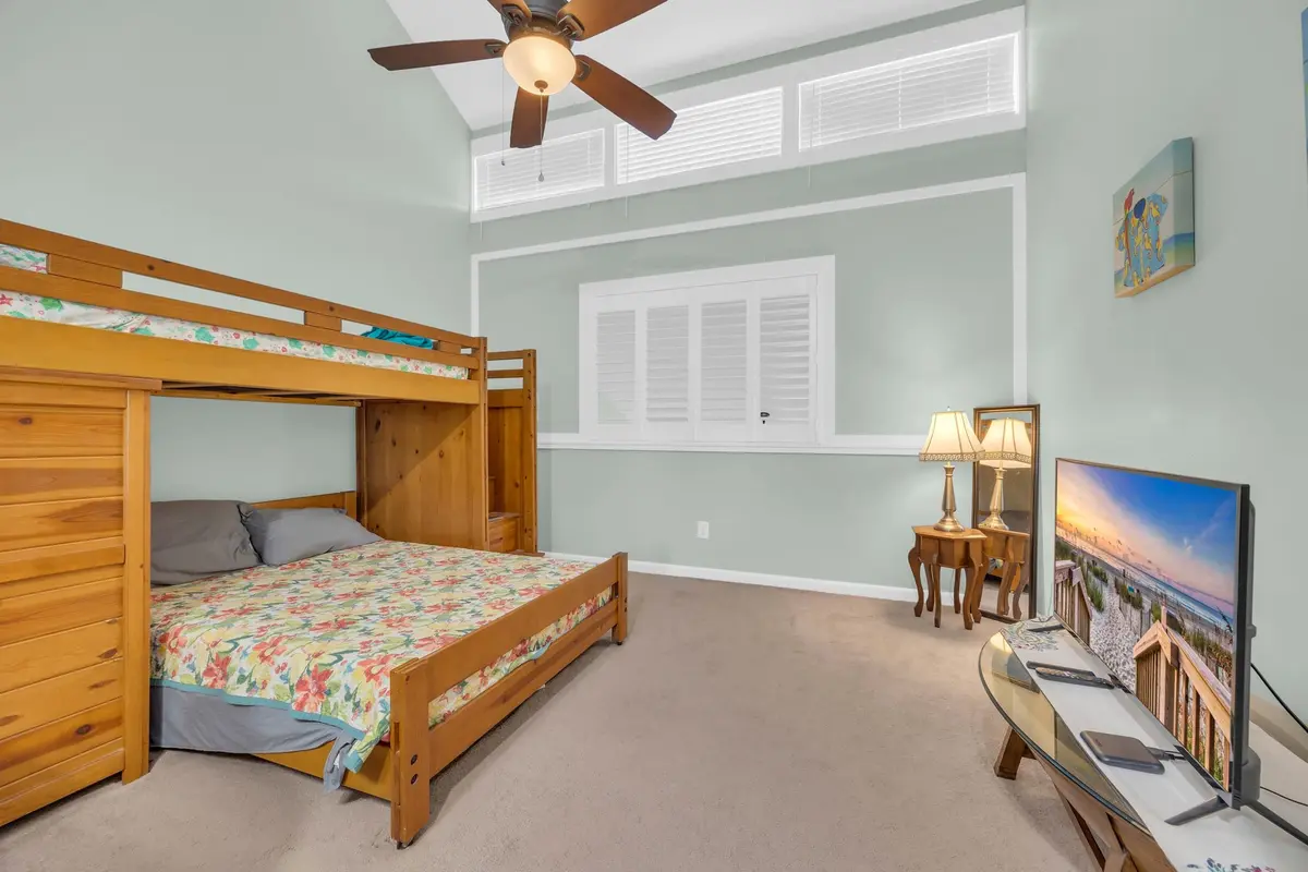 Upper-level bedroom with bunk beds, ceiling fan, and vaulted ceiling