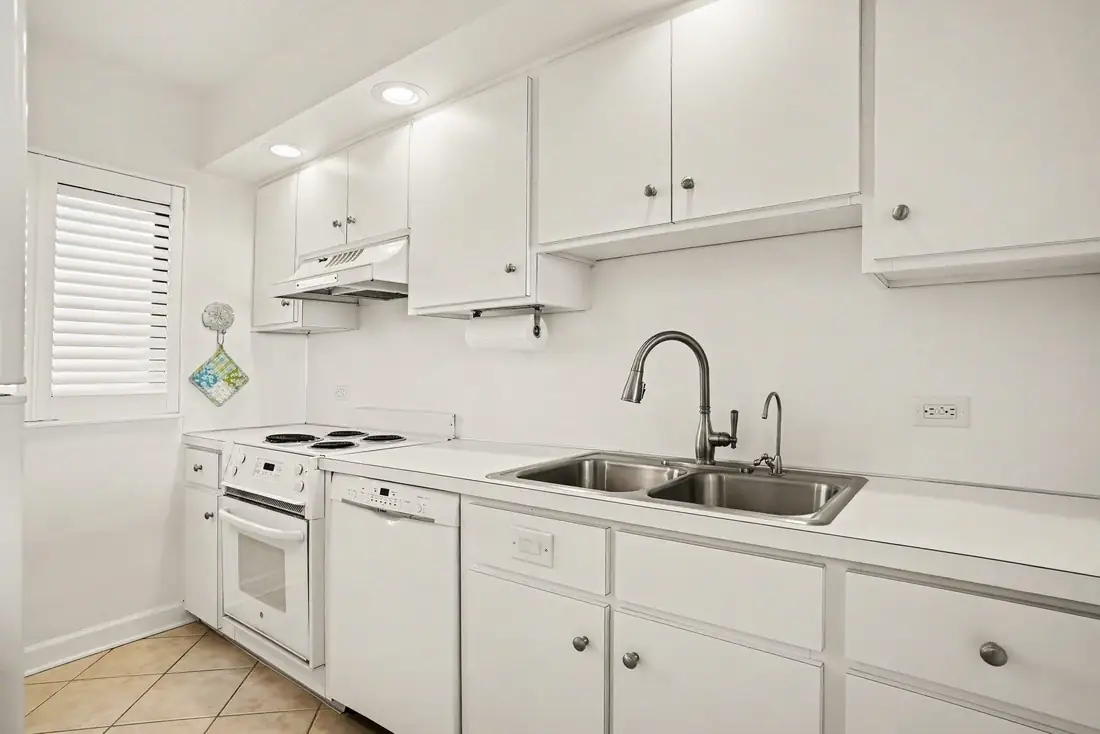 White galley kitchen with sink, cabinetry and appliances