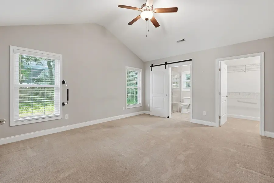 Primary bedroom with vaulted ceiling and ceiling fan