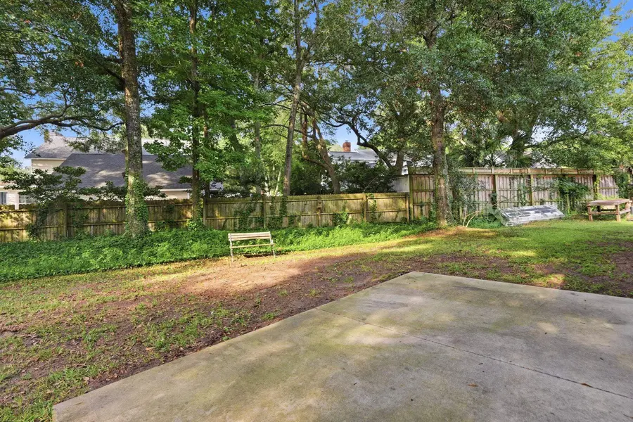 Fenced backyard with mature trees and patio