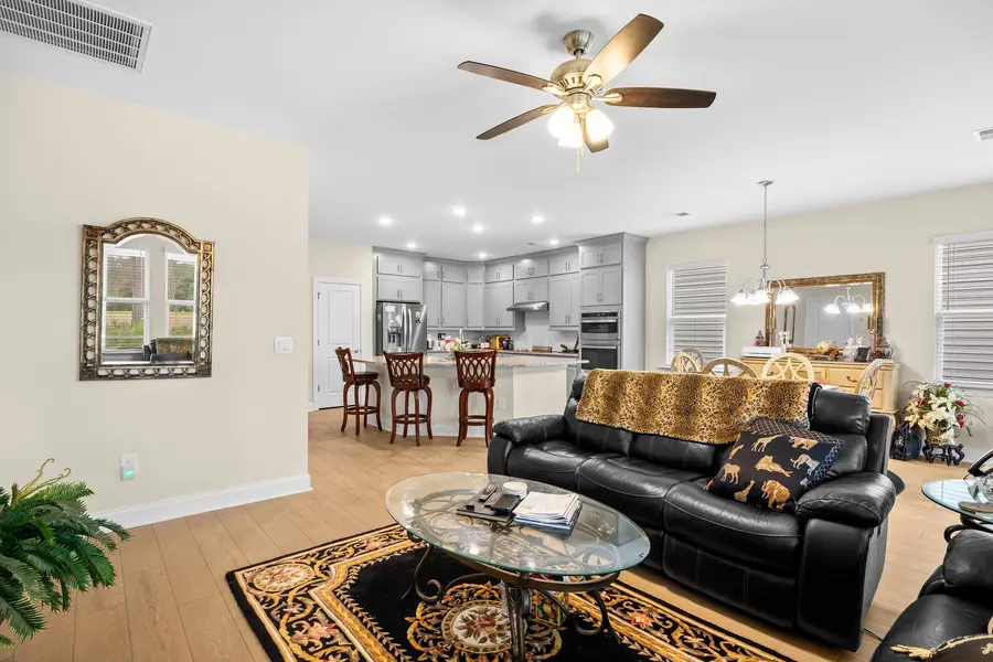 Open living room with golf-course windows and ceiling fan