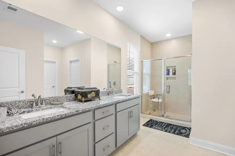 Primary bathroom with double vanity and tiled shower